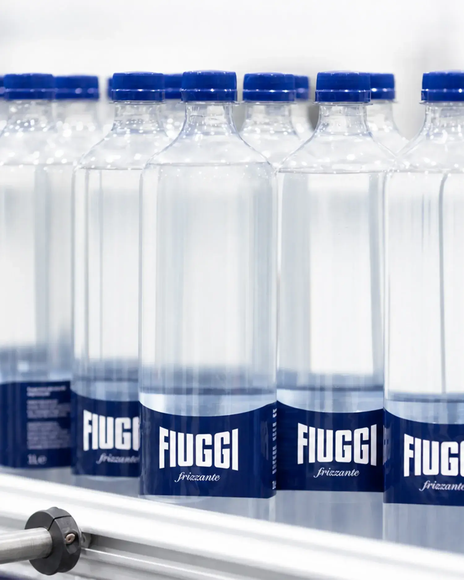 Acqua Fiuggi sparkling water bottles with blue caps on a production line