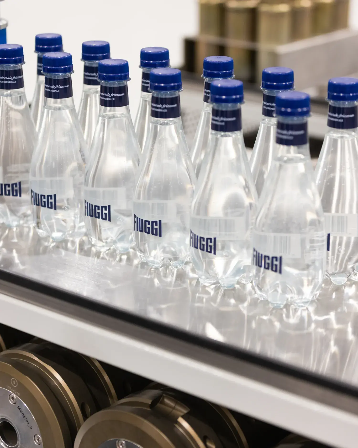 Acqua Fiuggi Premium sparkling water bottles with blue caps on a production line